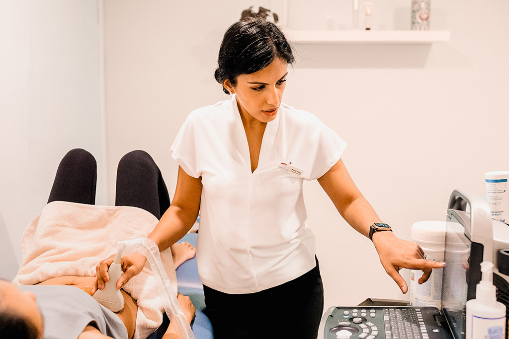 A physiotherapist setting up real time ultrasound beside a client in the treatment room